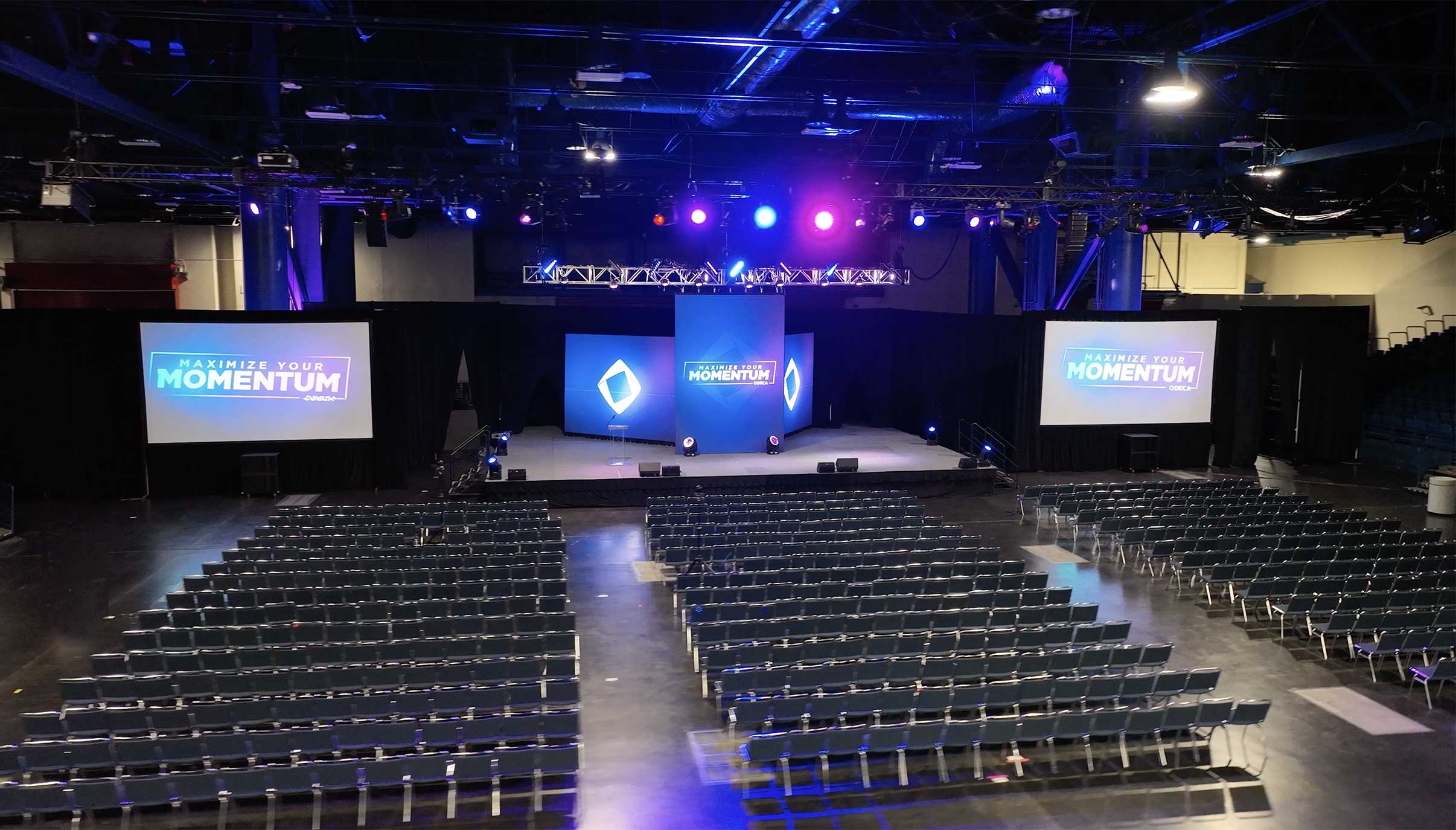 Empty auditorium with DECA momentum graphics projected on large screens
